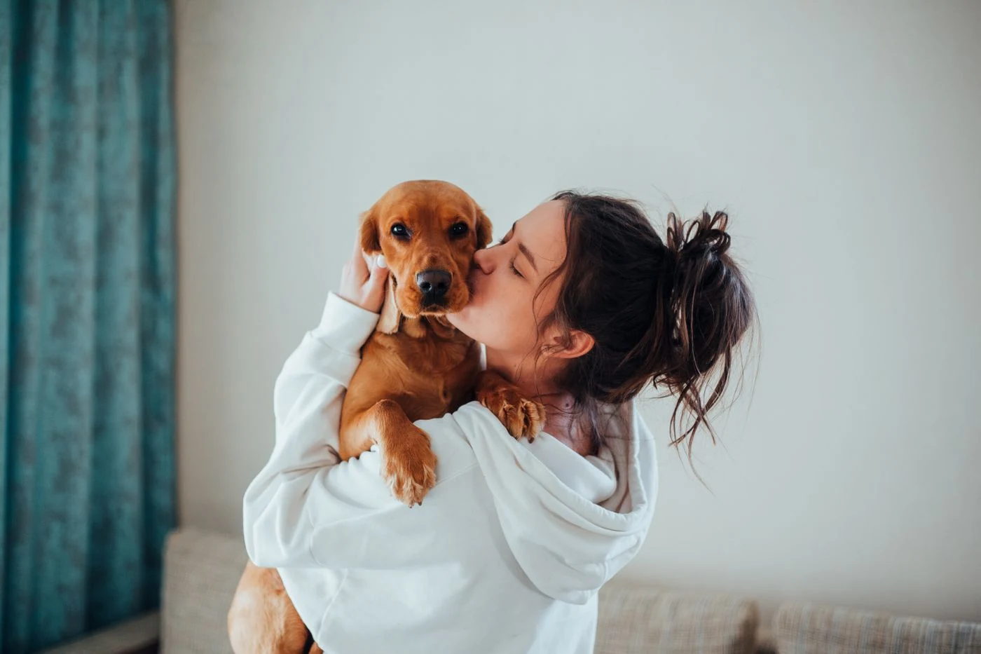 Mujer abrazando y besando a su perro en casa